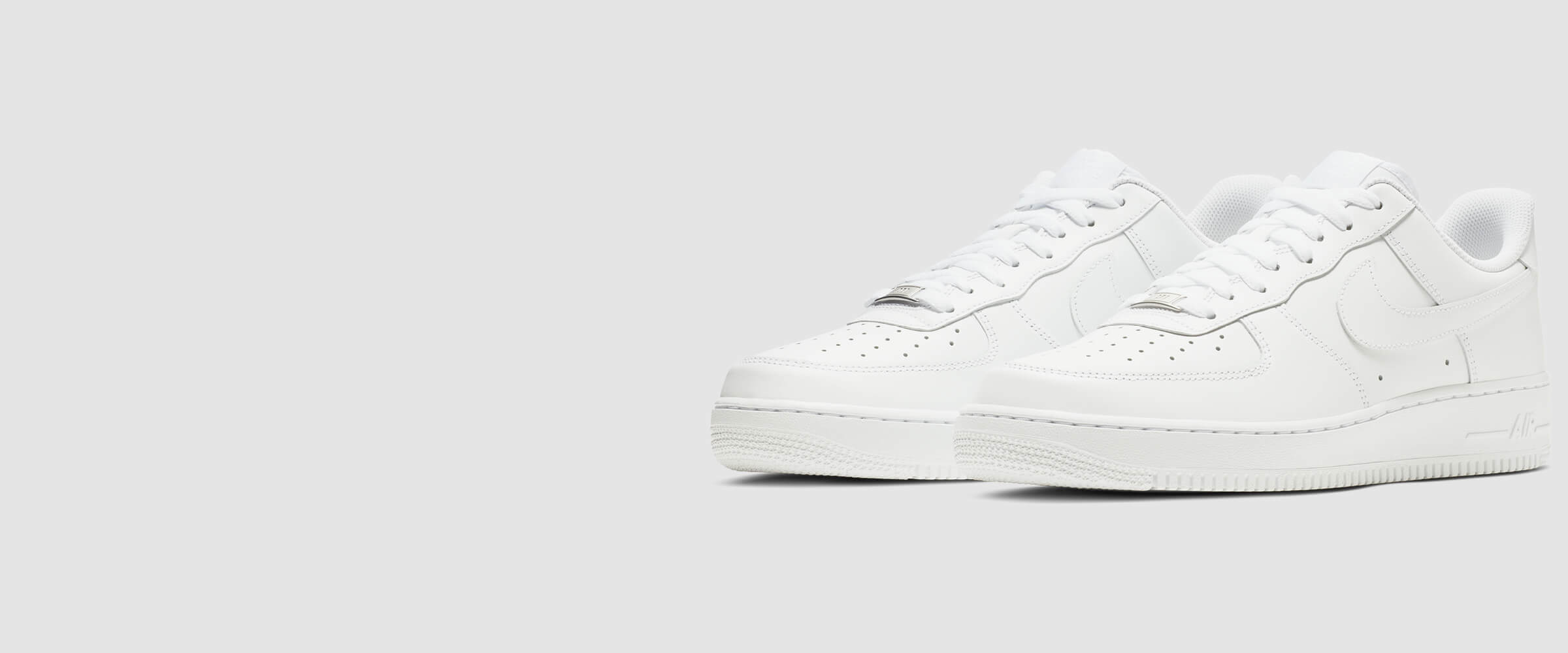 A pair of White Nike Air Force 1 Sneakers flat on ground